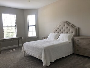 Cozy retreat with a large bed, desk, and nightstand, offering a comfortable space to unwind.