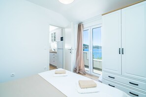 A room with a bed, a wardrobe, and a view of the sea.
