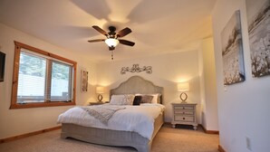 A bedroom with a bed, a ceiling fan, a nightstand, and a window with blinds.