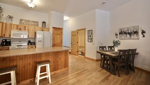 A modern kitchen with wooden cabinets, a central island, and a dining area with a table and chairs.
