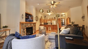 A living room with a fireplace, a television, and a dining area in the background.