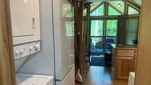 A compact kitchen with a built-in oven, a refrigerator, and a sink. There is a window with curtains, and a view of the outdoors. - Magical Forest Cabin- Secluded Retreat Near Beach (Lakebay)