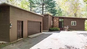 A two-story building with a garage, a covered porch, and a stone wall.