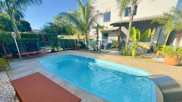 Een buitenzwembad, ligstoelen bij het zwembad