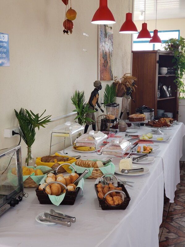 A buffet table with various food items and a decorative statue. - Cambará Suites (Bonito)