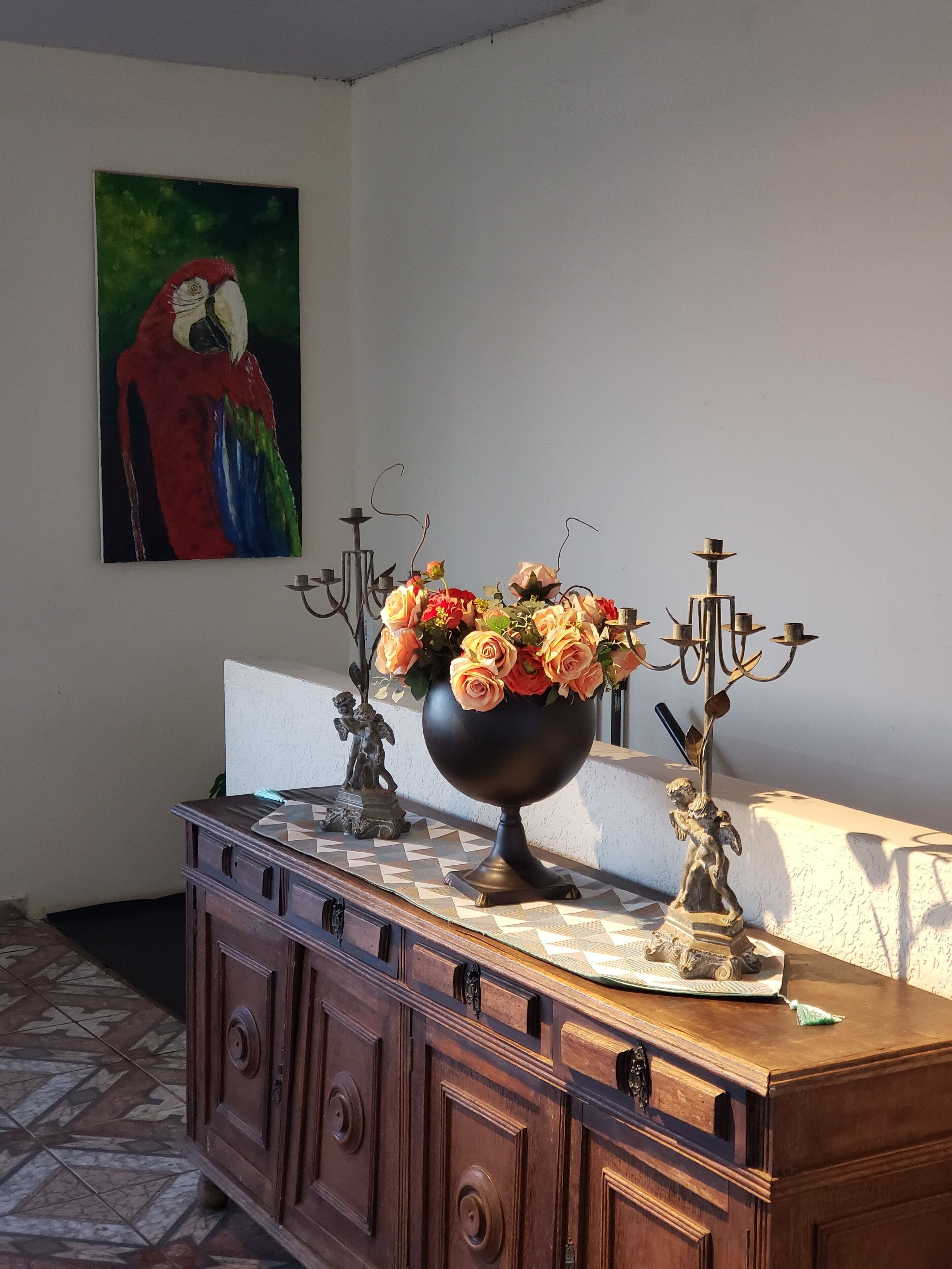 A wooden cabinet with a vase of flowers and two candelabras on top.