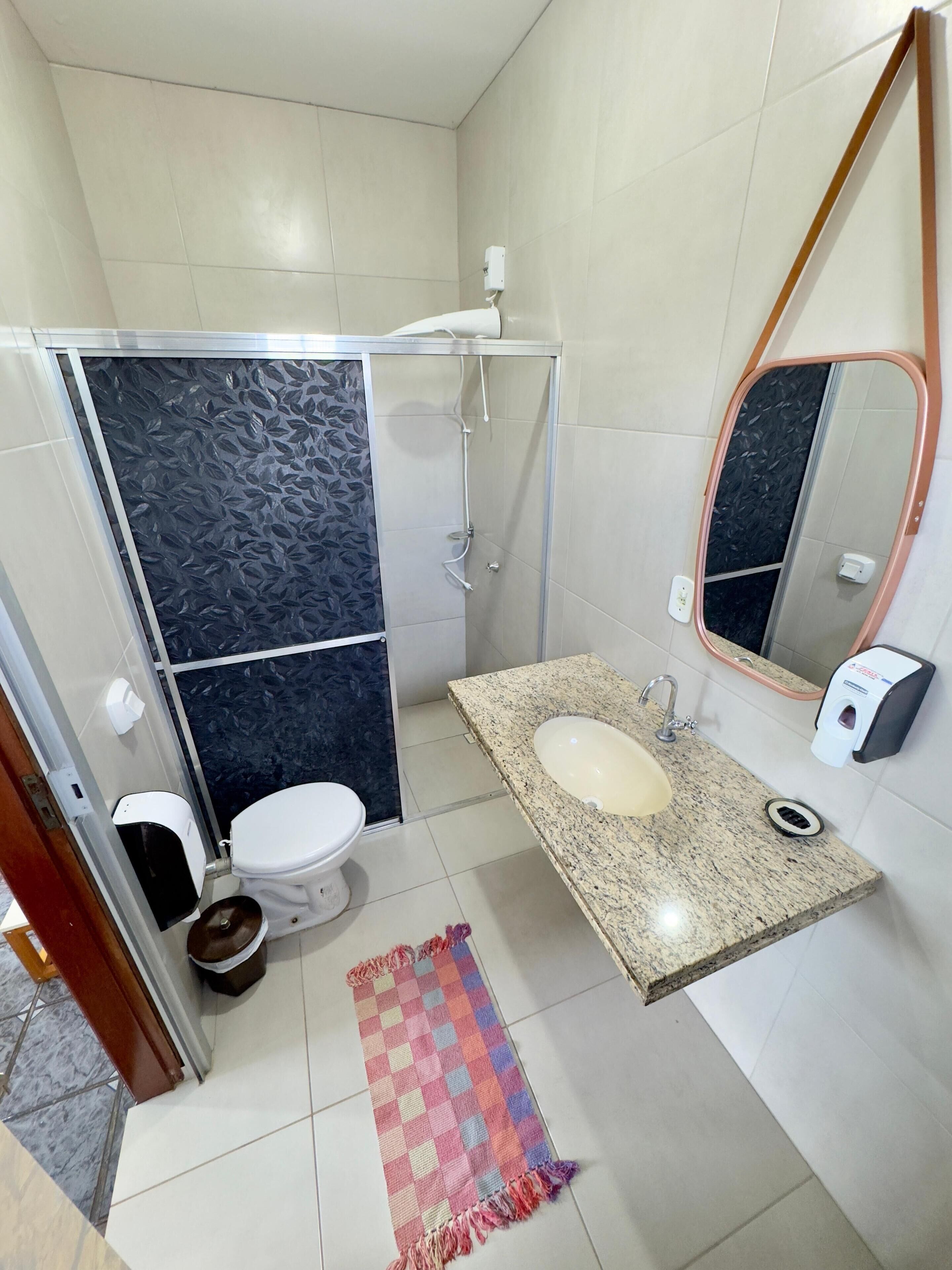 Une salle de bain avec des toilettes, un lavabo et une douche.