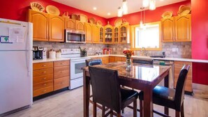 Una cocina con armarios de madera, una isla central y un comedor con sillas.
