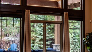 Una habitación amplia con ventanas grandes, techo de madera y una zona de estar acogedora.