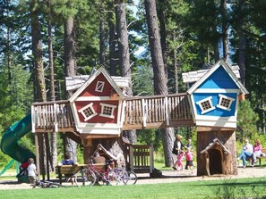 A playground with wooden playhouses and a slide.