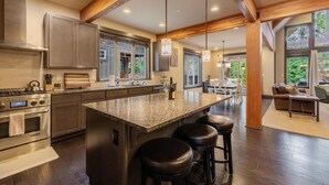 Una cocina moderna con encimeras de granito, electrodomésticos de acero inoxidable y una isla grande con taburetes.