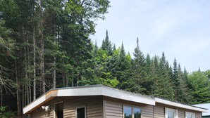 A mobile home with a garage, a truck parked in front, and a forested background. - 1 Bedroom house with direct trail access (Errol)