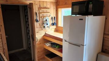 Una cucina compatta con pareti in legno, un fornello bianco, un frigorifero e un forno a microonde.