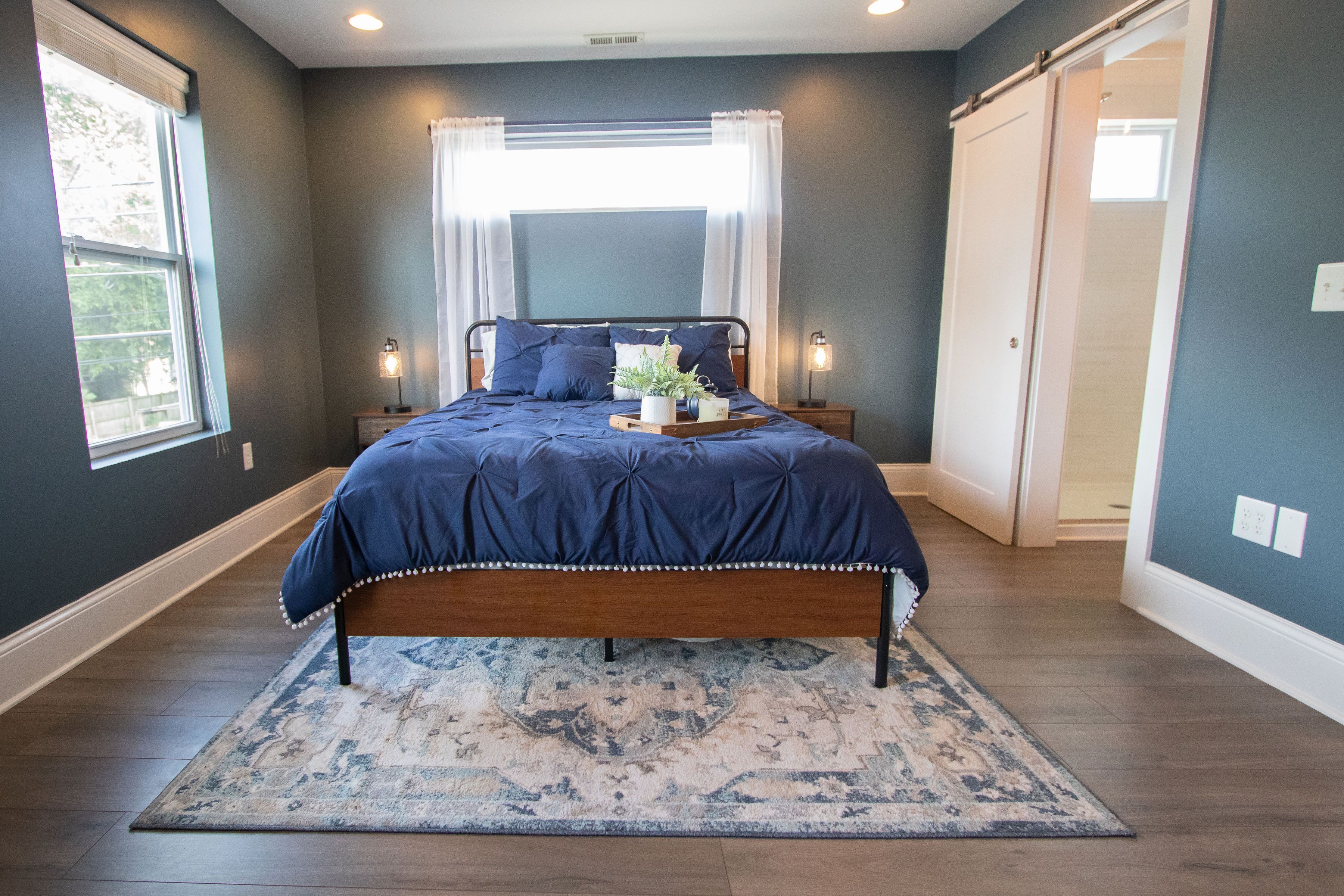 A bedroom with a bed, nightstands, a window, and a door.