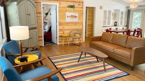 A cozy living room with a sofa, chairs, a coffee table, and a colorful striped rug.