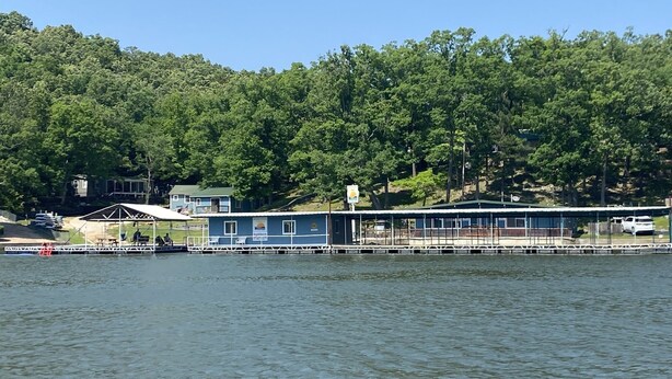 A lakeside building with a dock, surrounded by dense forest.