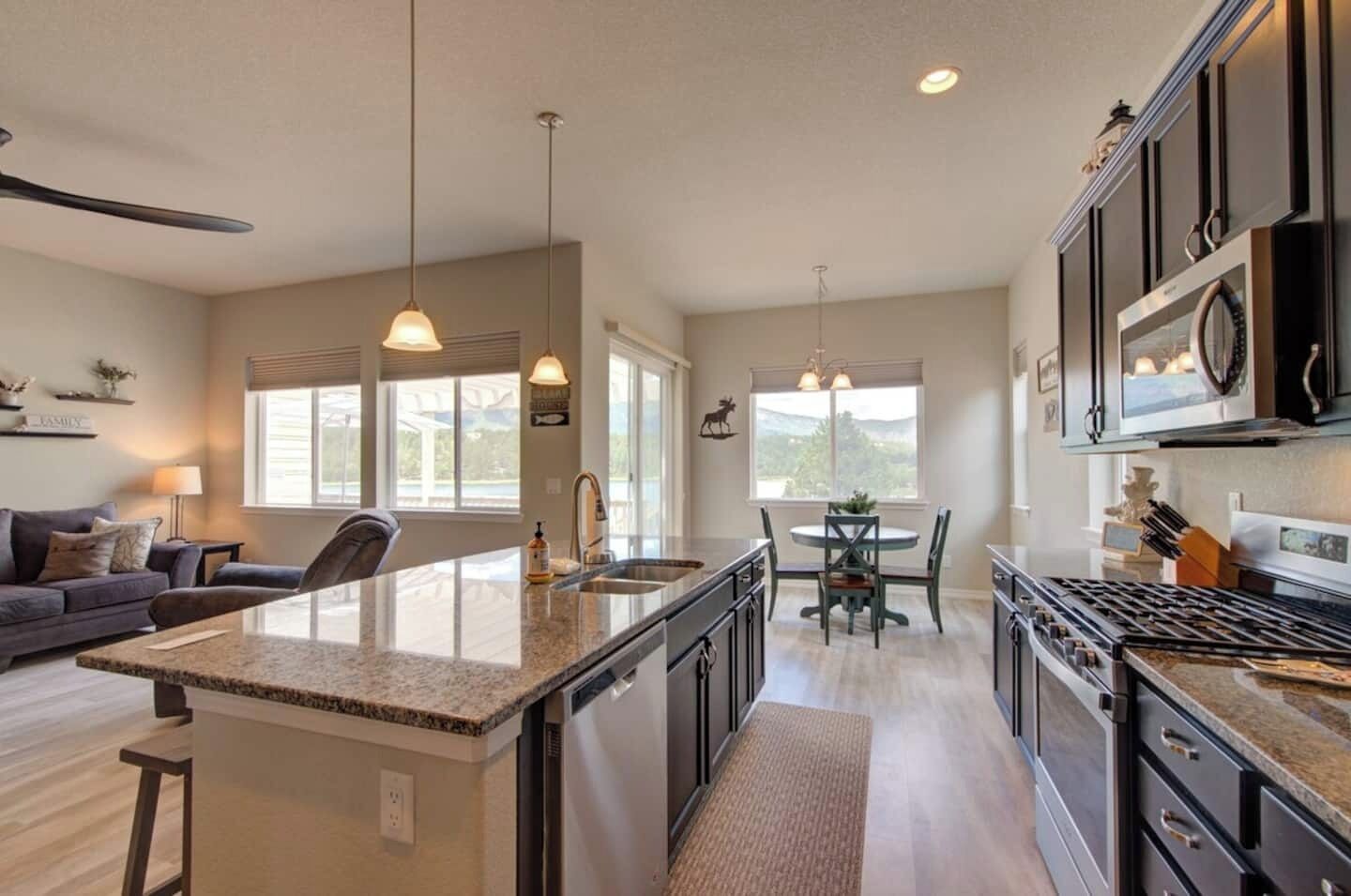 A spacious kitchen with a central island, a dining area with a table and chairs, and a living area with a sofa and a lamp.