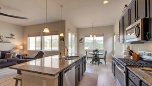 A spacious kitchen with a central island, a dining area with a table and chairs, and a living area with a sofa and a lamp. - ON THE LAKE Monument & USAFA Mountain View Home. 30 DAY MINIMUM (Monument)