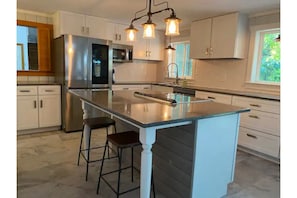 Enjoy cooking in this well-equipped kitchen with a central island, stainless steel appliances, and ample natural light.