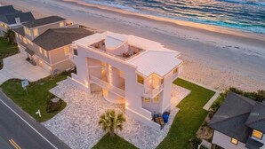 Une propriété située en bord de mer, comprenant une maison à deux étages, une allée et une pelouse.