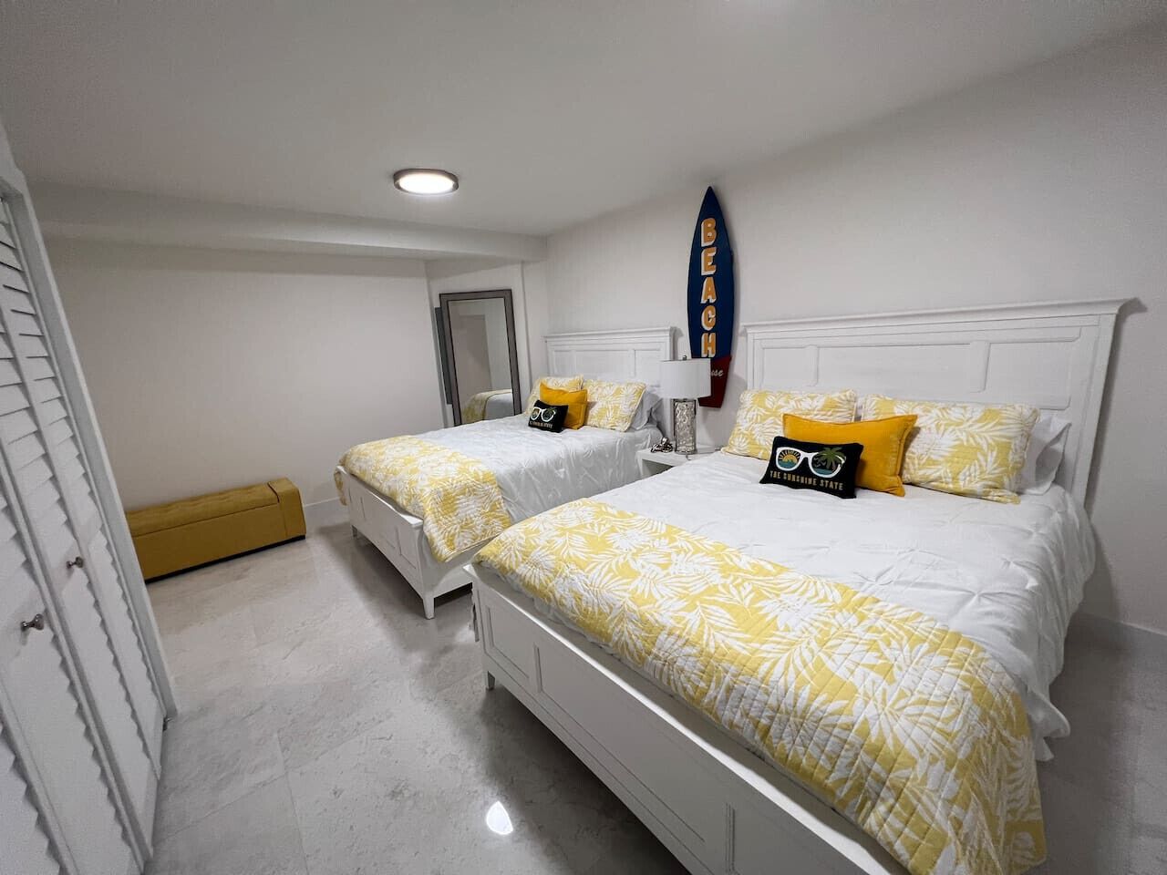 Un dormitorio con dos camas individuales, ropa de cama blanca y una decoración con una tabla de surf.