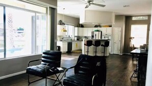 A spacious living area with a large window, a ceiling fan, and a kitchen in the background. - Scenic Lakeside Cove House (Glendale)