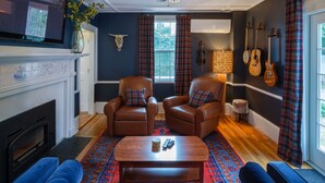 A living room with a fireplace, two leather armchairs, a blue sofa, and a coffee table.
