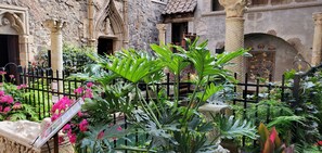 A courtyard with stone architecture, a black metal fence, and lush green plants. - Sally Webster Inn (Rockport)