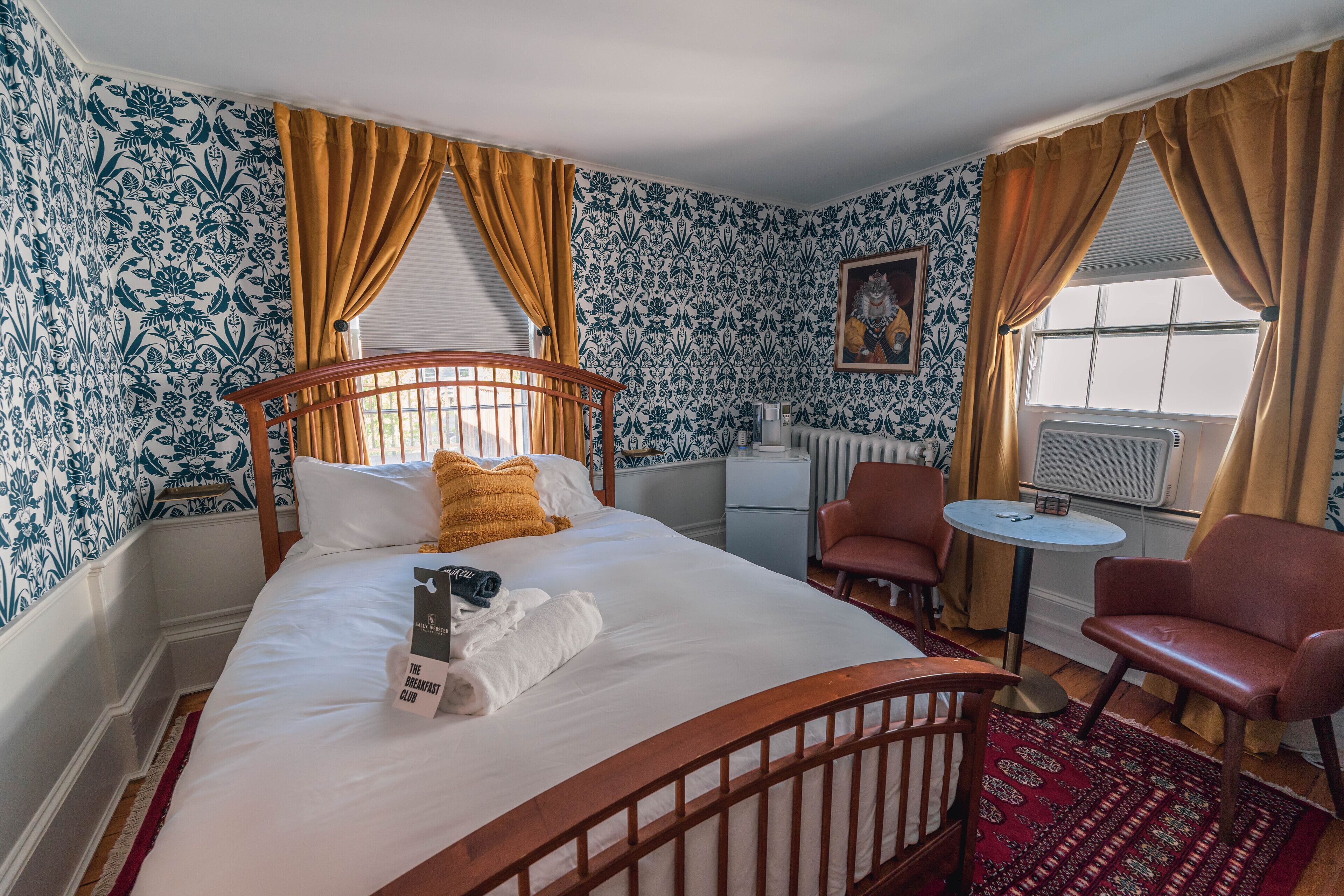 Una habitación de hotel con una cama, una mesita, dos sillas y un radiador.