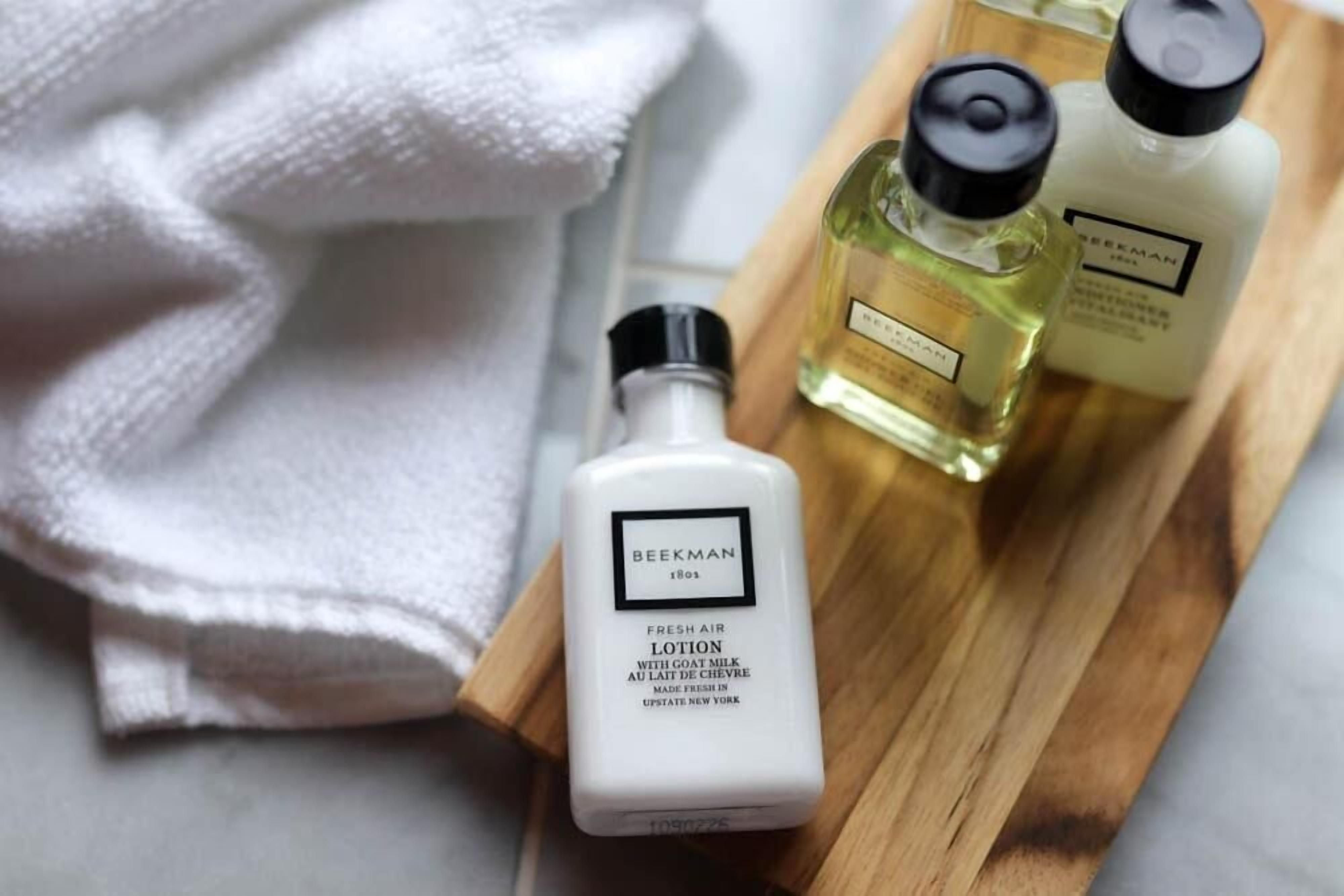 A bottle of Beekman 1803 Fresh Air Lotion with goat milk on a wooden tray.