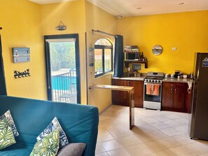 Een ruimtelijk ingerichte leefruimte met een kitchenette, een eethoek en uitzicht op de omgeving.