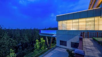 A modern building with a flat roof and large windows, surrounded by greenery.
