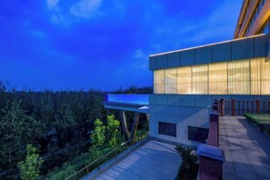 Un edificio moderno con tejado plano y ventanas amplias, rodeado de vegetación.