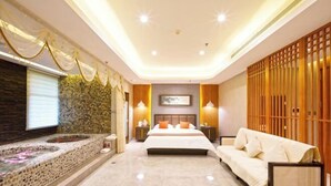 A modern hotel room with a large bed, a seating area, a decorative wall, and a small water feature. - Hebei Yeshengyuan Hotel (Pingshan)
