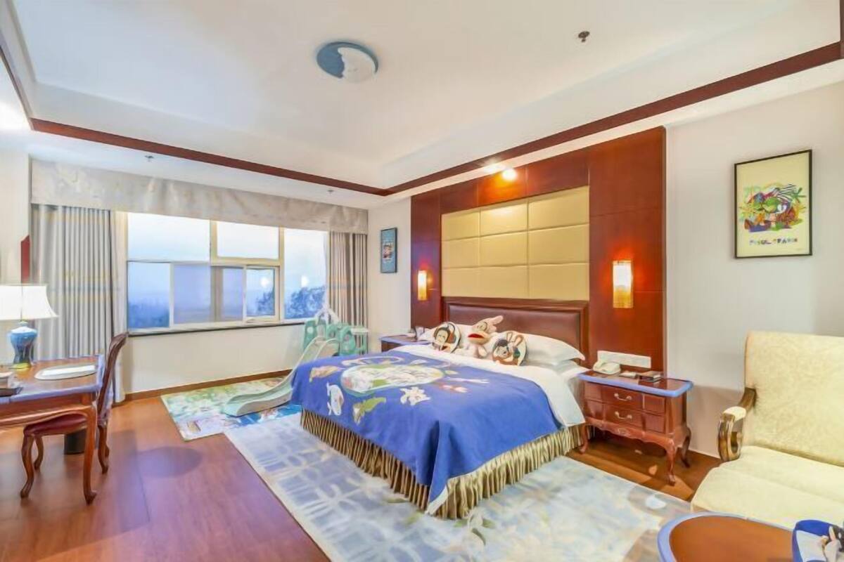 A hotel room with a large bed, a desk, a chair, and a sofa.
