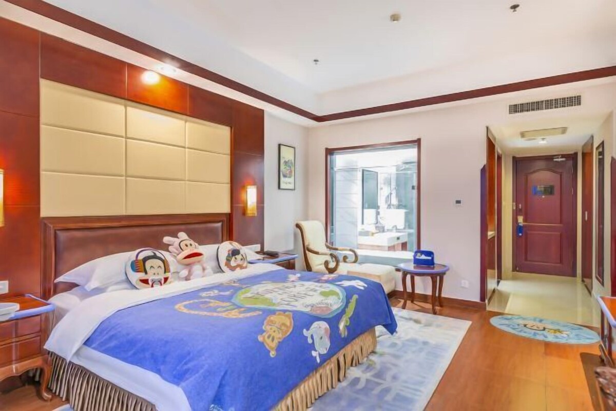 Habitación de hotel con una cama grande, cabecera de madera, escritorio y una silla.