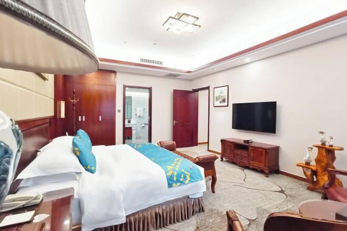 A hotel room with a bed, a TV, a desk, and a chair.