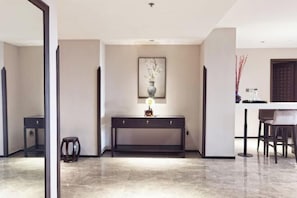 A modern interior with a dark console table, a vase with flowers, and a dining area with chairs.