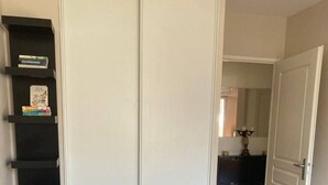 Un dormitorio con dos camas, un armario y una estantería.
