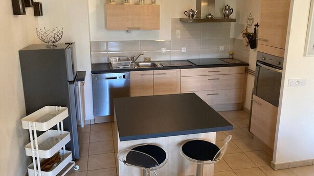 Una cocina moderna con una isla central, horno empotrado y lavavajillas.