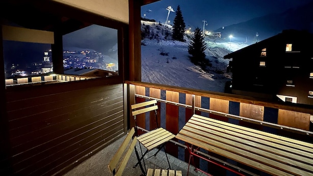 A balcony with wooden benches and a view of a snowy mountain area at night. - New! Beautiful duplex "ski in ski out" La Clusaz center  (La Clusaz)