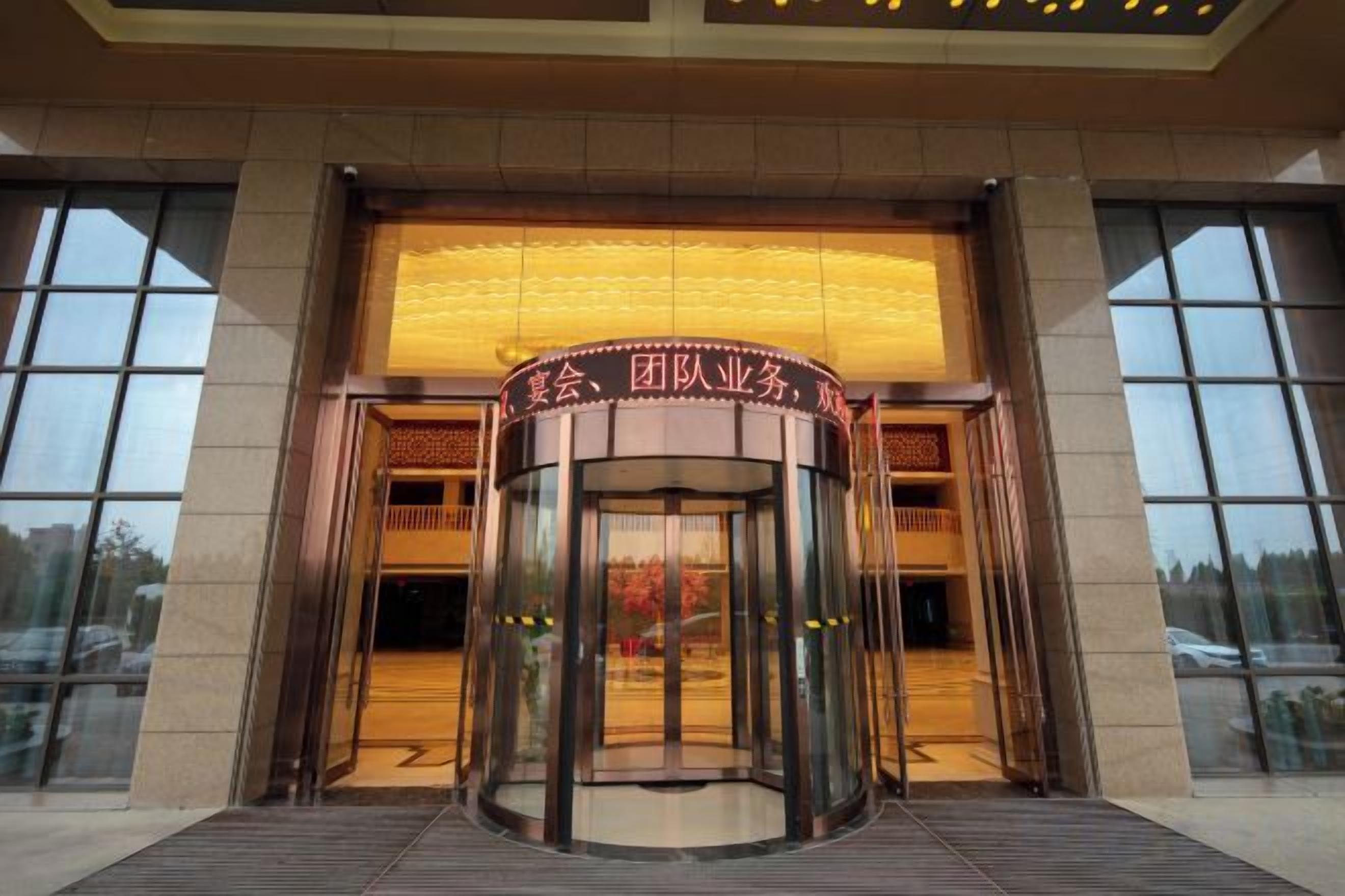 A revolving door entrance with a sign above it.