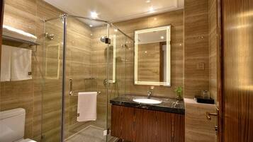 A bathroom with a glass-enclosed shower, a sink with a mirror, and wooden wall panels.