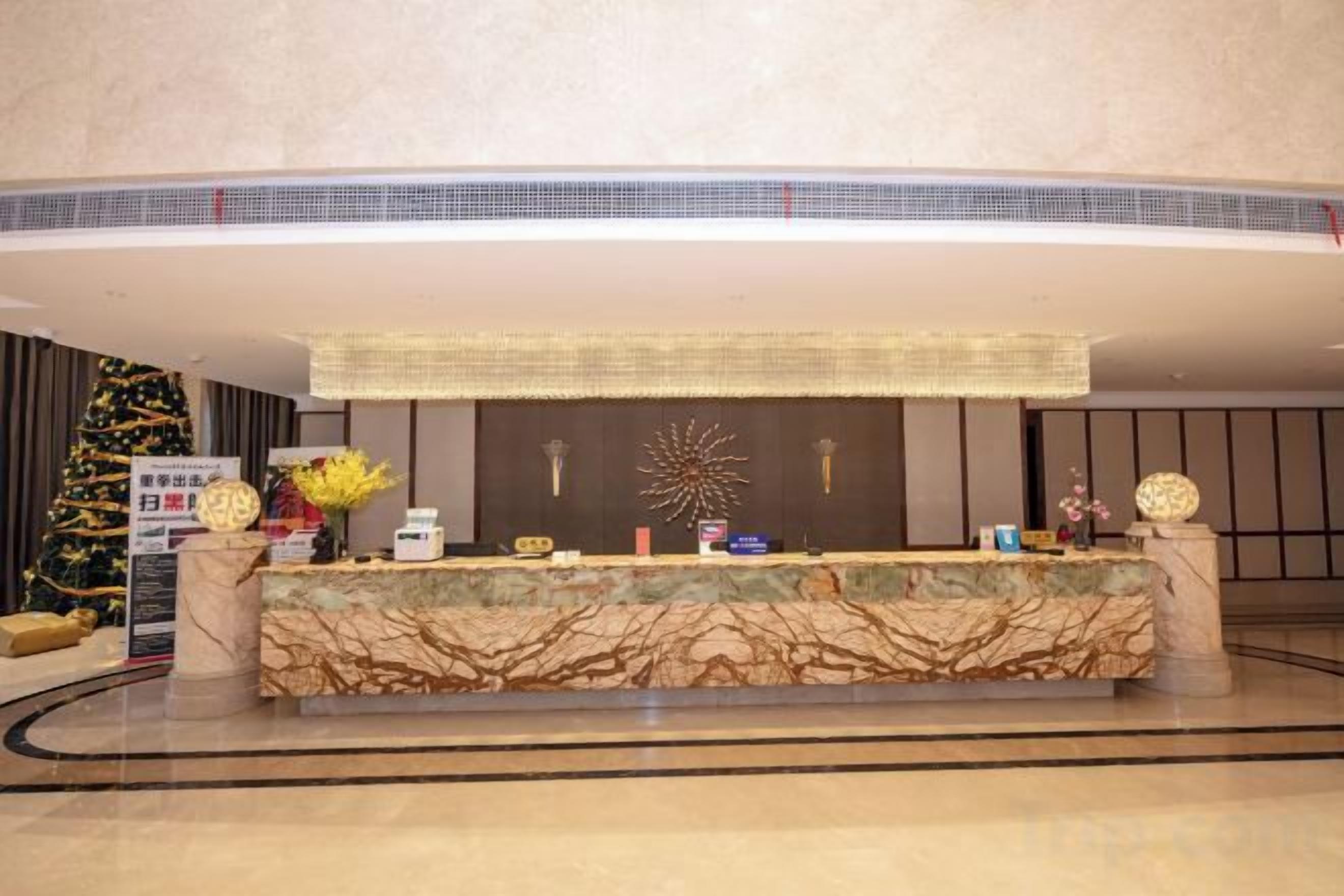 A hotel reception area with a marble counter, a Christmas tree, and a decorative wall.