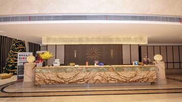 A hotel reception area with a marble counter, a Christmas tree, and a decorative wall.