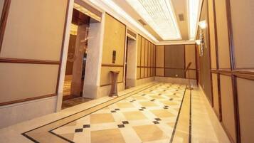 Un pasillo con piso estampado, puertas y una lámpara.