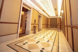 A corridor with a patterned floor, doors, and a light fixture. - Jiade Hotel (Tongxiang)