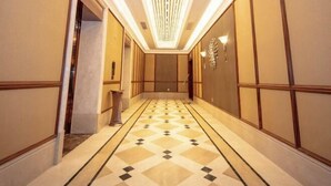 Un pasillo con piso estampado, un candelabro y una lámpara fijada a la pared.