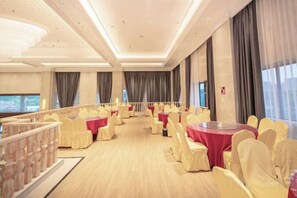 Un salón de banquetes con mesas y sillas redondas, un balcón y un ventanal grande.