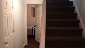 Käytävä, jossa on matoilla päällystetyt portaat, jotka johtavat ylätasanteelle.